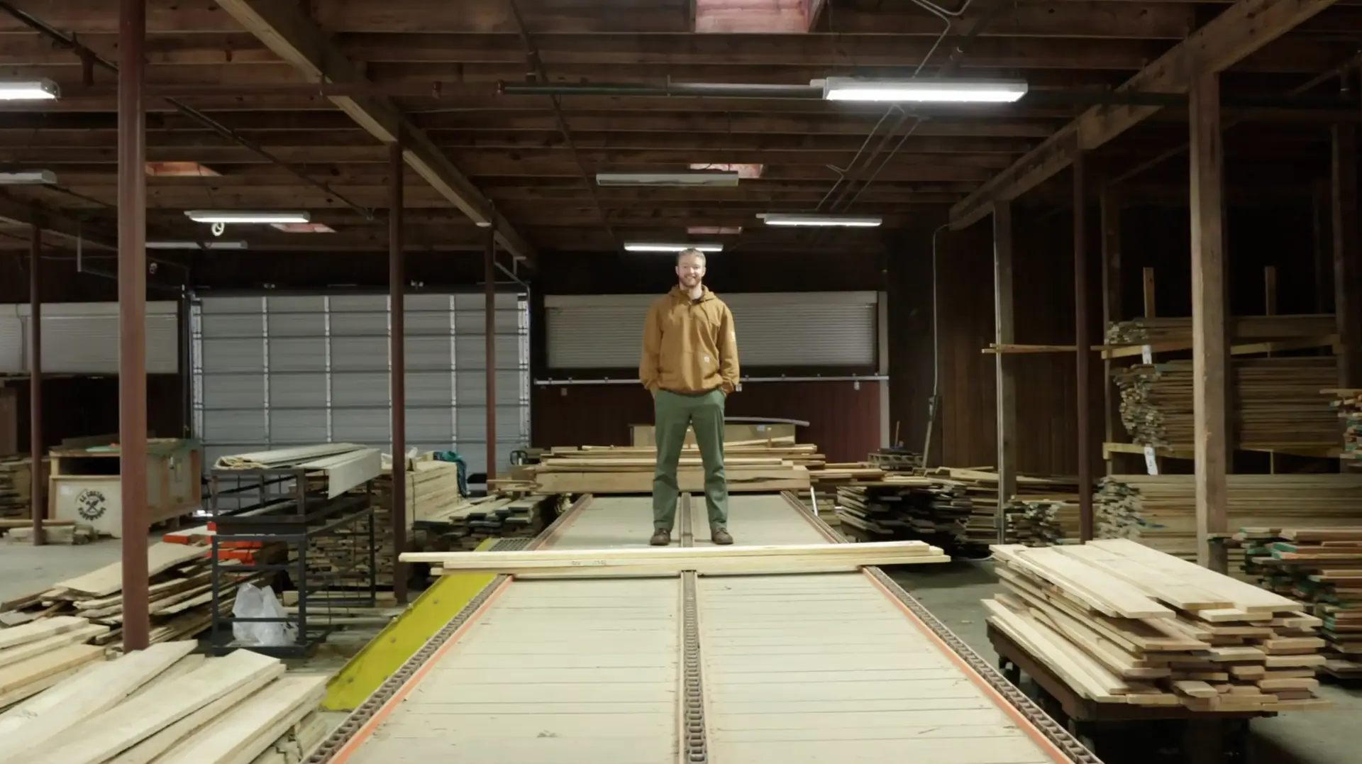 Ben Christensen standing on stacks of logs at a sawmill
