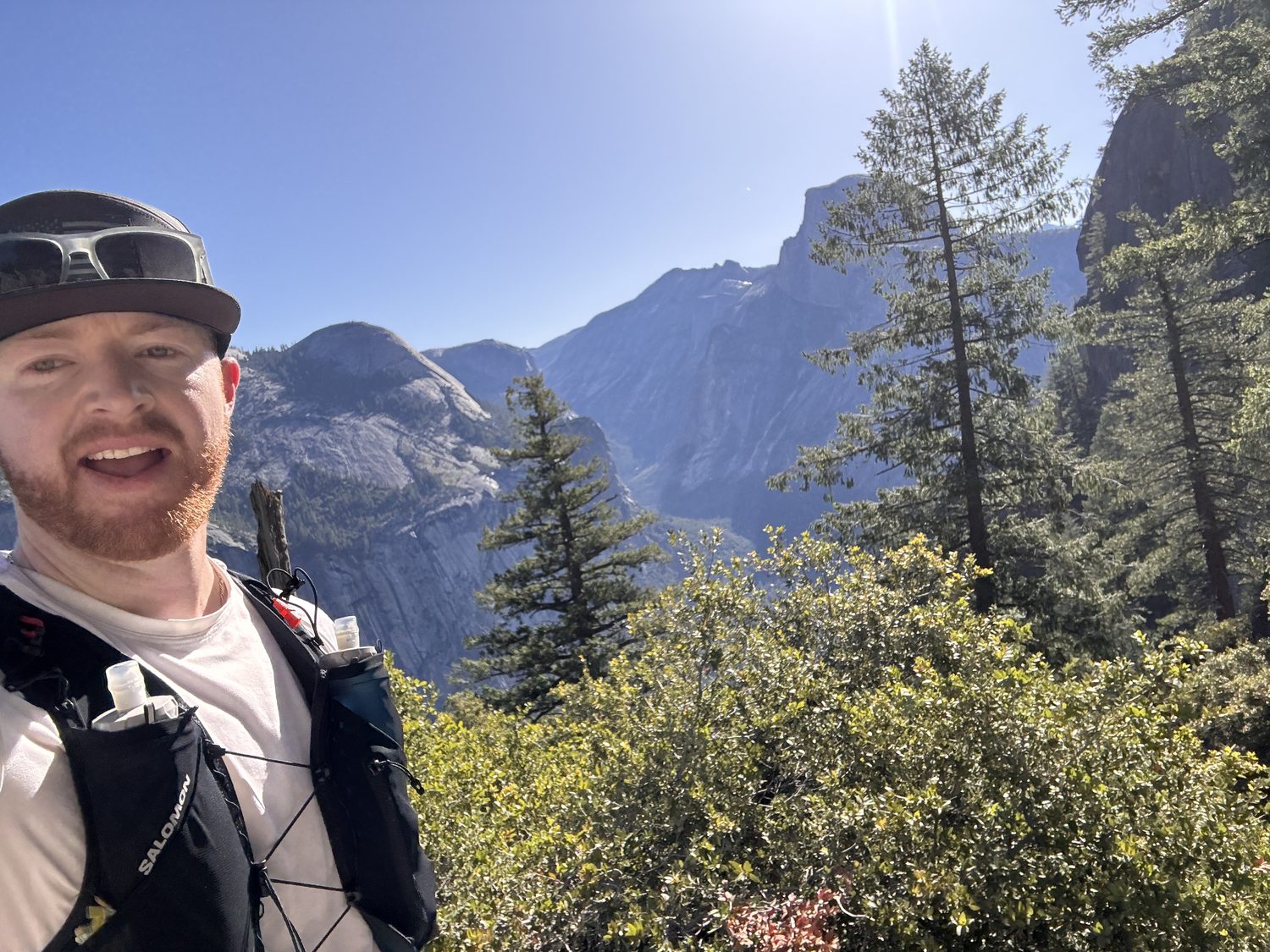 Ben Christensen on a trail run in Yosemite, Half Dome behind him