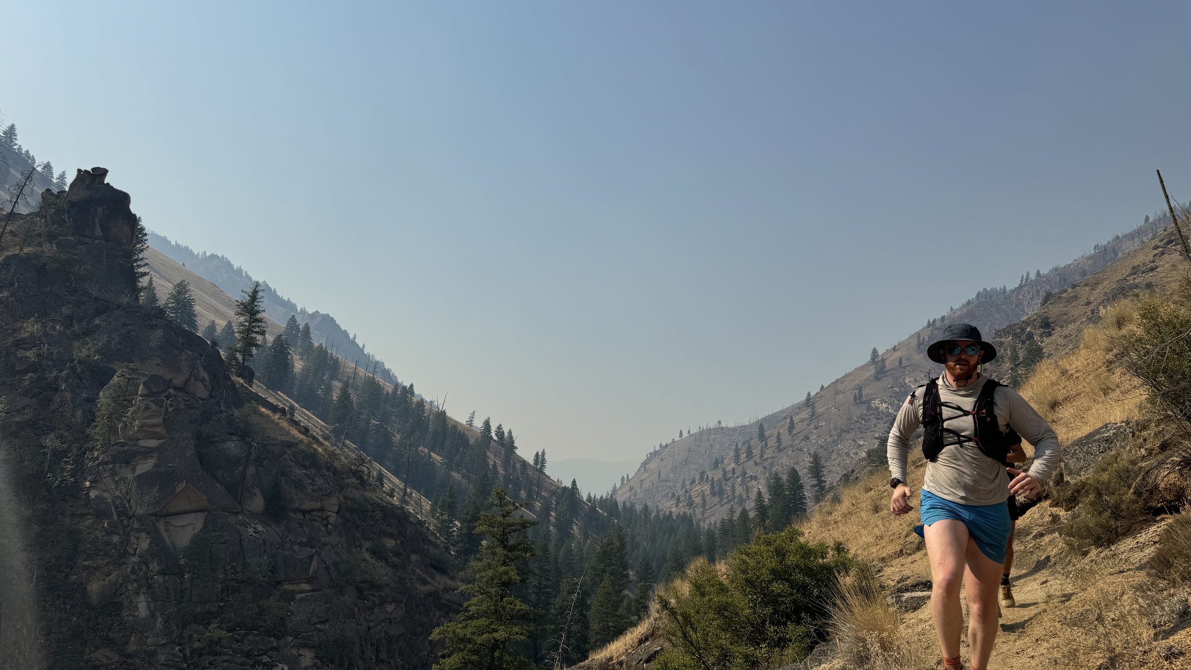 Ben Christensen running a mountain trail through a fire-scarred canyon